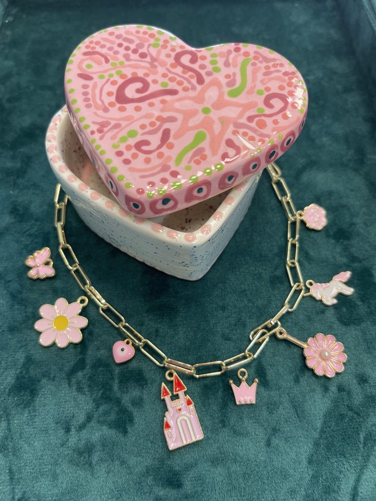 Charm bracelet beside a painted heart-shaped jewelry box