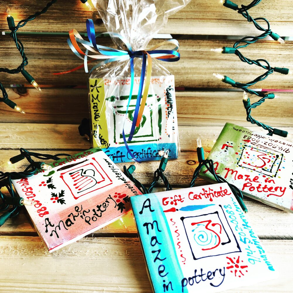 Hand-painted ceramic A Maze In Pottery gift certificates, one wrapped with ribbon