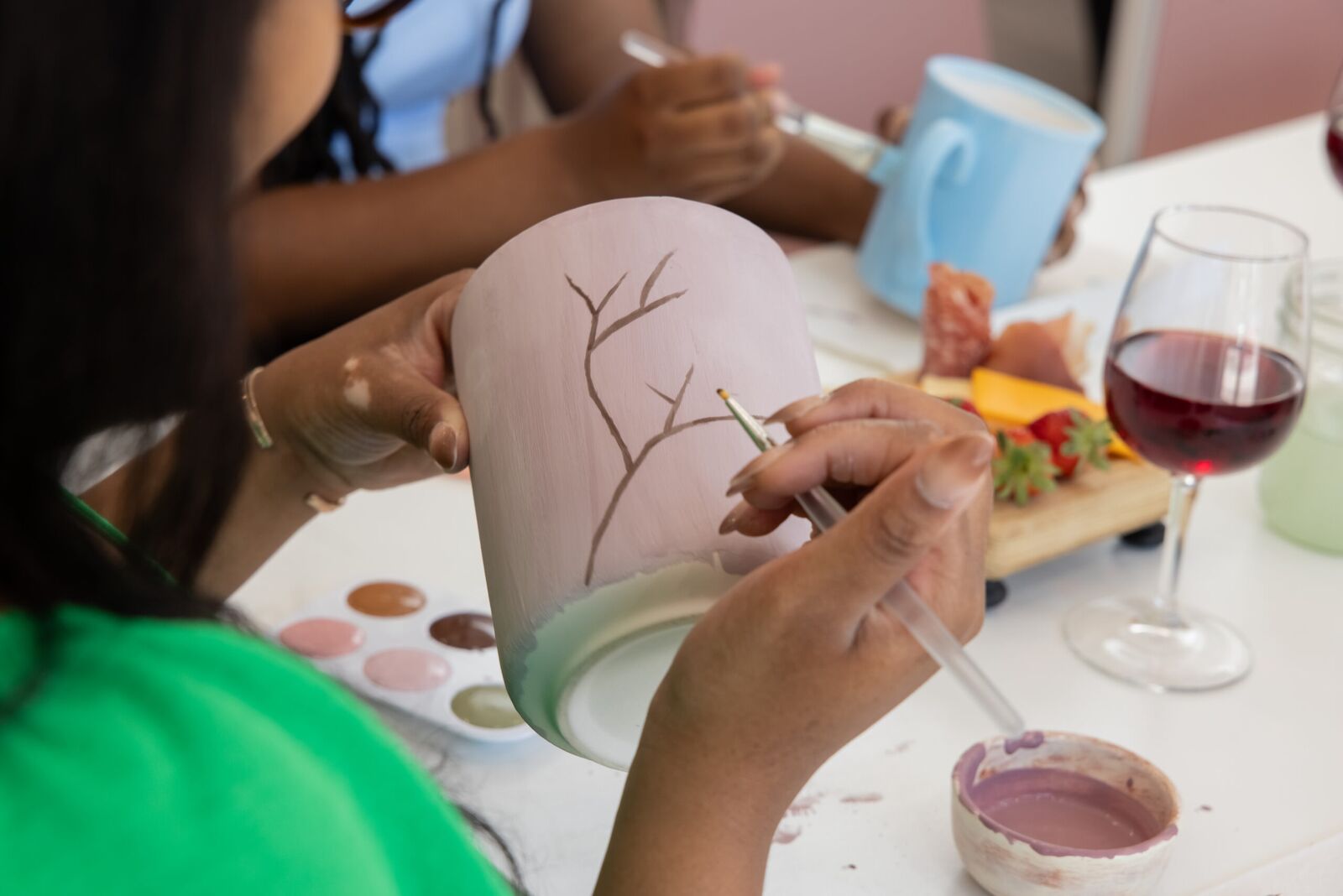 Painting a mug beside a glass of red wine and a cheese board