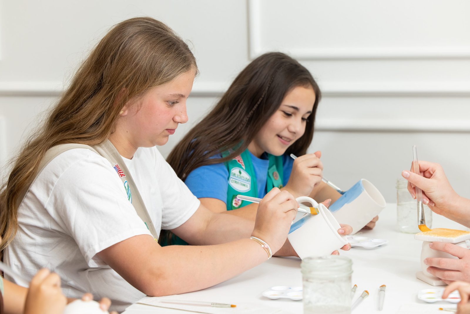 Two Girl Scouts painting pottery at the studio