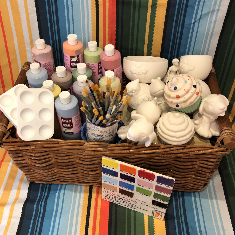 Pottery Party To Go basket with paints, brushes, a color chart and pieces to paint