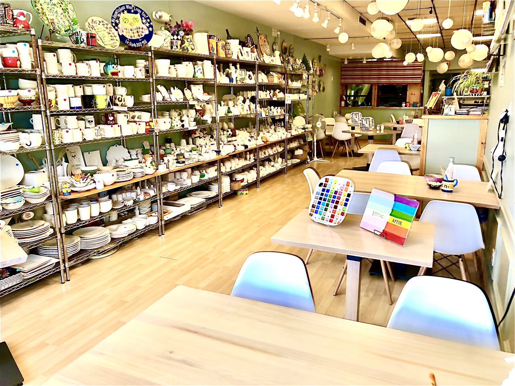 Inside the studio: shelves of unpainted pottery along one wall and painting tables by the window