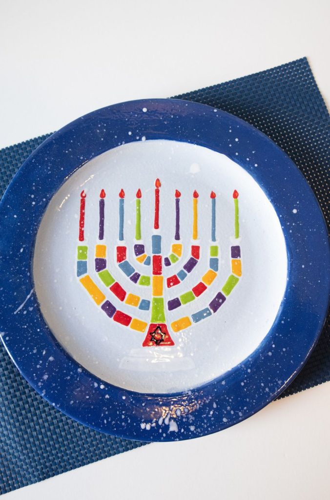 Hand-painted Hanukkah plate with a colorful mosaic menorah and a speckled deep blue rim