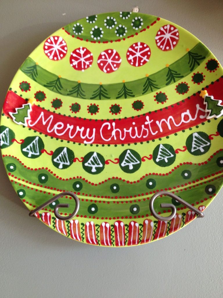 Round Merry Christmas plate painted like an ornament with snowflakes, trees and red and green stripes