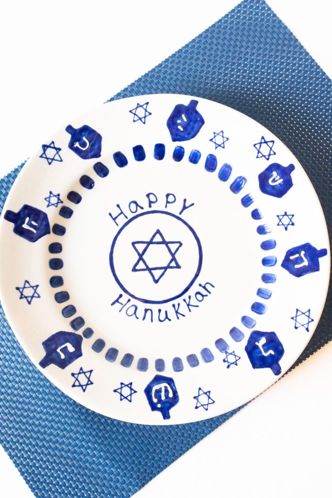 Hand-painted Happy Hanukkah plate with a Star of David, dreidels and a ring of blue candles