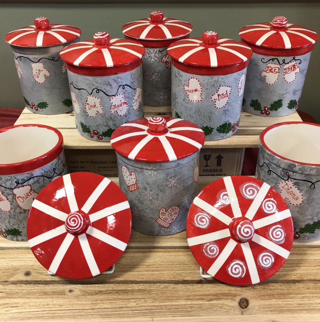 Gray hand-painted holiday canisters with candy-stripe lids, mittens, holly and family first names