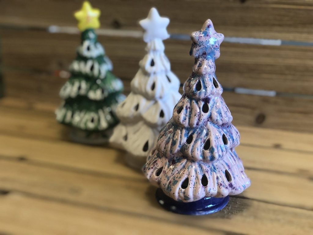 Three hand-painted ceramic Christmas trees in green, white and lavender with glowing star toppers