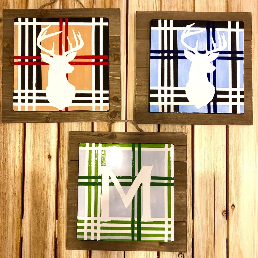 Hand-painted plaid tiles in rustic wood frames with white deer head silhouettes and a letter M