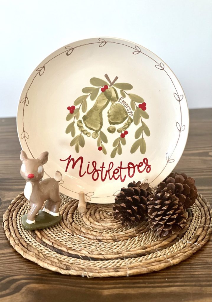Hand-painted Mistletoes plate with green footprint mistletoe and red berries on a rustic table setting