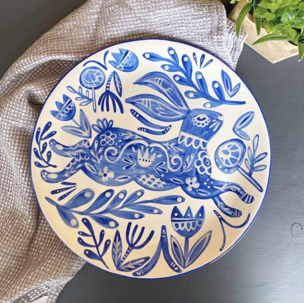 Hand-painted white plate with a leaping blue folk-art rabbit surrounded by tulips and leaves