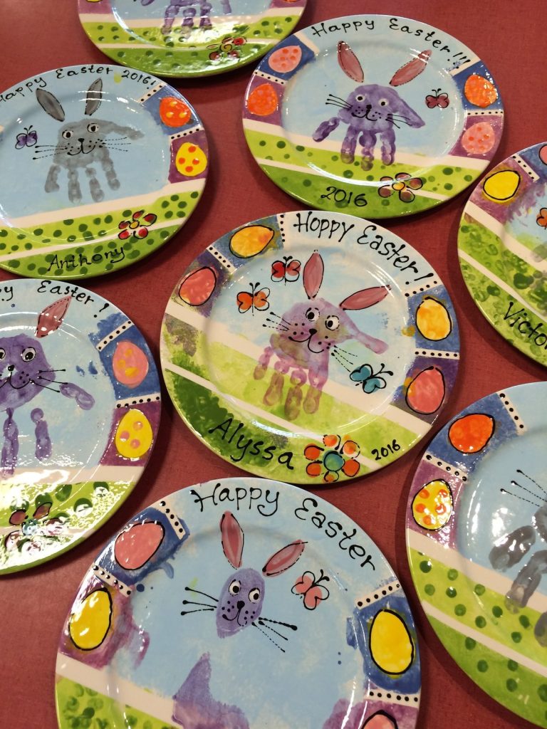 Hand-painted Happy Easter plates with handprint bunnies, colorful eggs and green grass borders