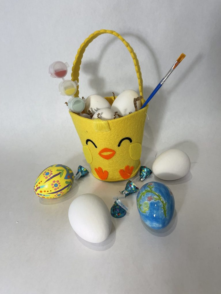 Easter paint kit in a yellow chick basket with bisque and painted eggs, paints and a brush