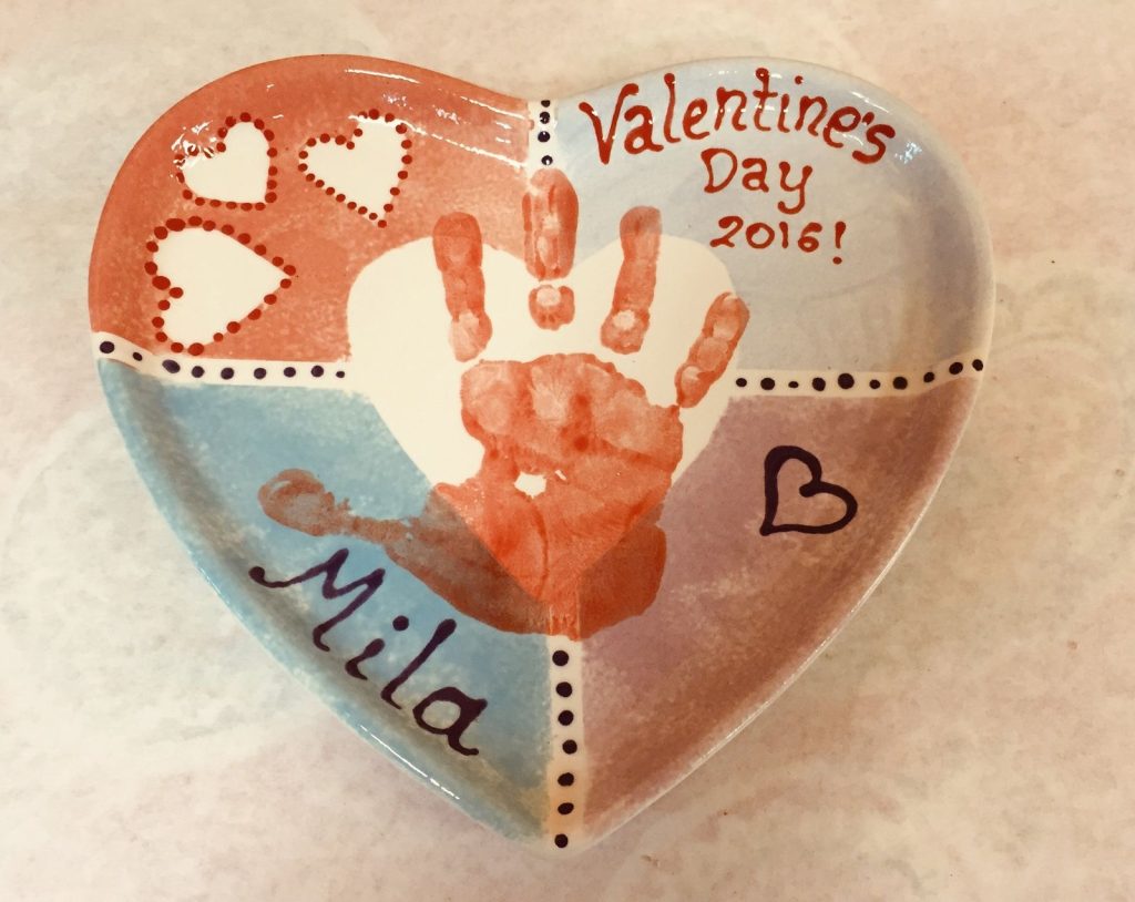 Heart-shaped Valentine's Day dish with orange handprint inside a heart on colorblock background