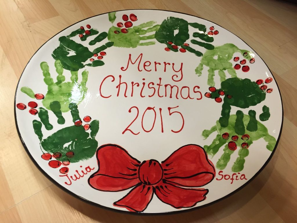 Round Merry Christmas plate with green handprint wreath and big red bow