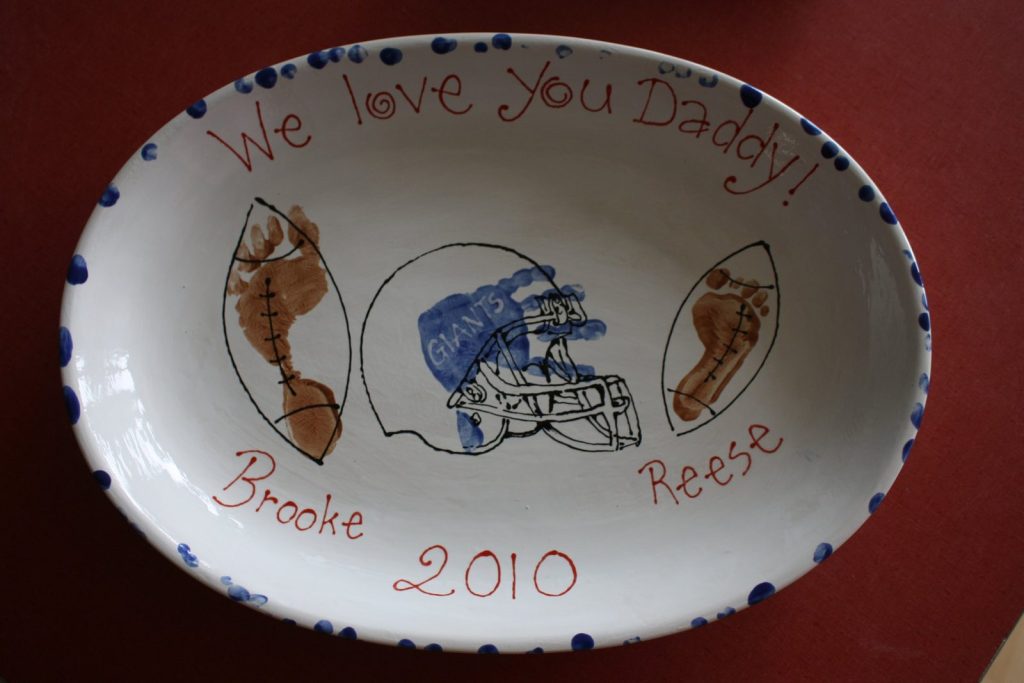Hand-painted oval We love You Daddy bowl with footprint footballs and a blue helmet, dated 2010
