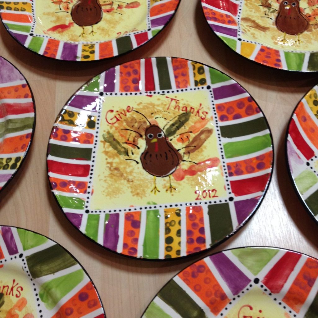 Hand-painted Give Thanks plates with handprint turkeys and bright multicolor striped rims