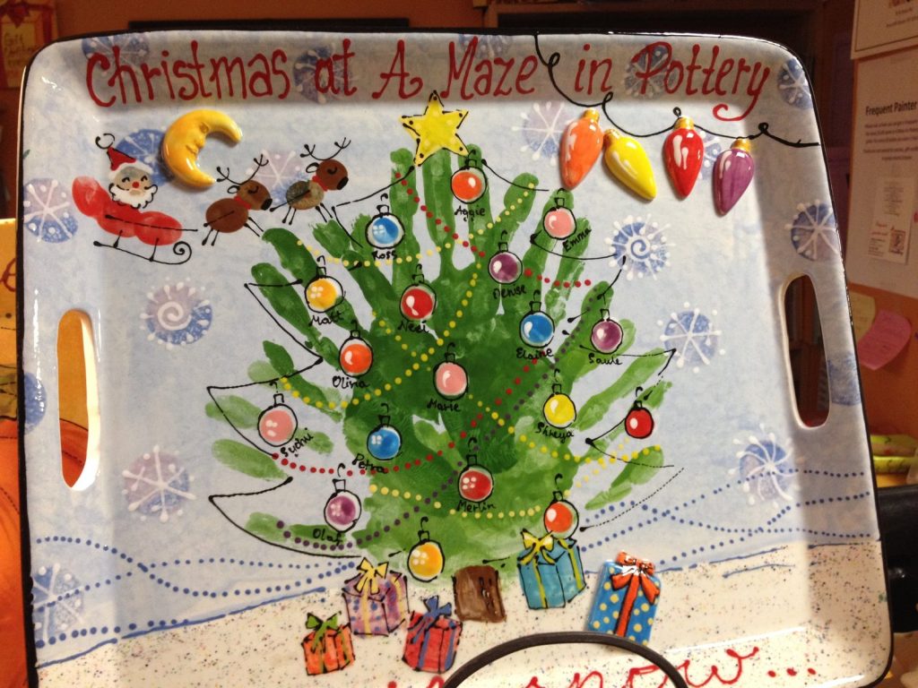 Hand-painted handled tray reading Christmas at A Maze in Pottery with a handprint tree and string lights