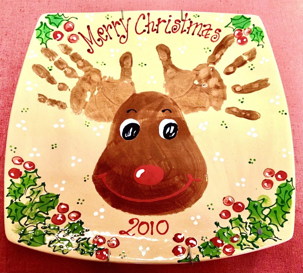 Hand-painted Merry Christmas platter with a handprint antler reindeer and holly border, dated 2010
