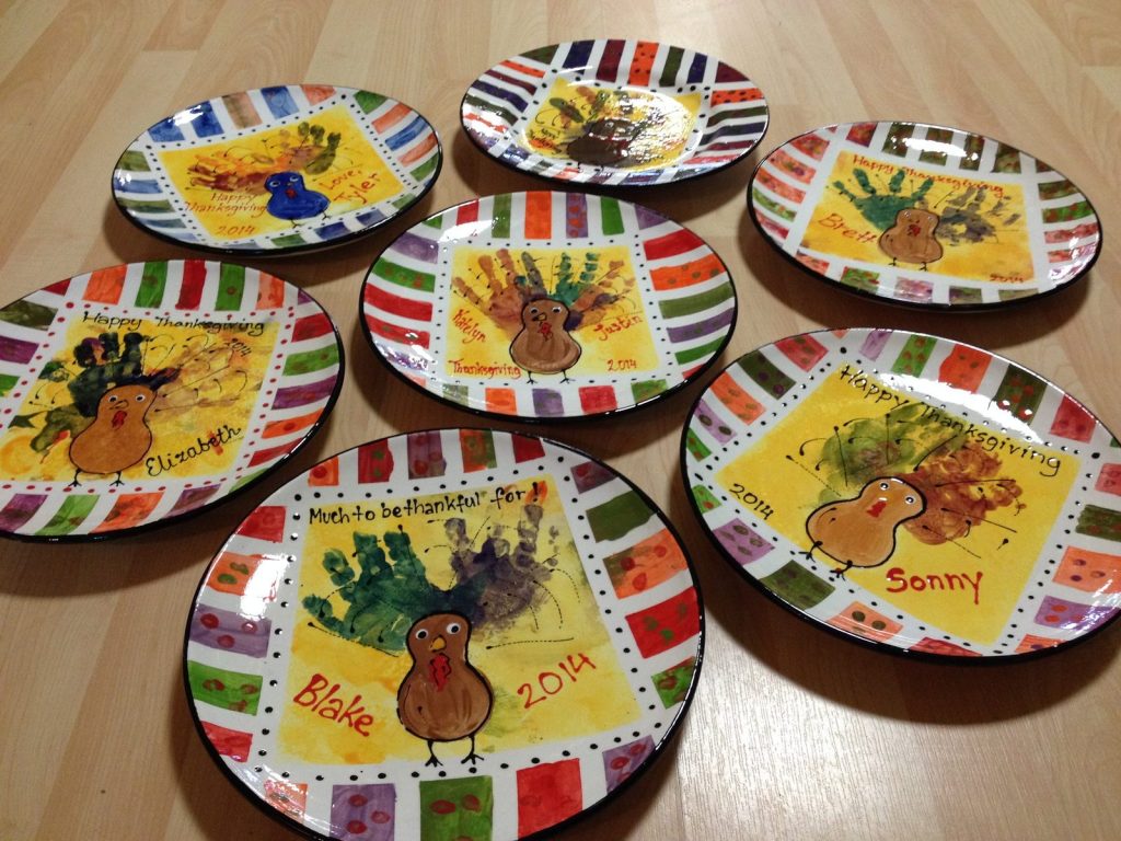 Set of hand-painted Thanksgiving plates with handprint turkeys and bright striped borders