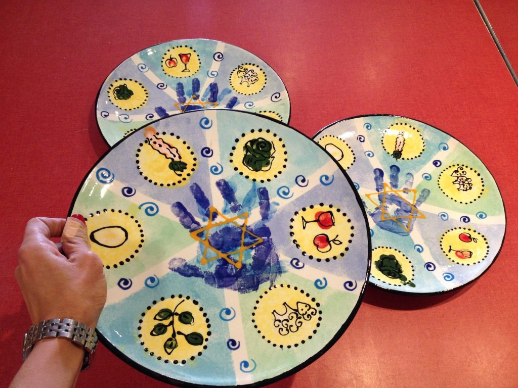 Hand-painted round plates with blue handprints, swirls and yellow medallion designs