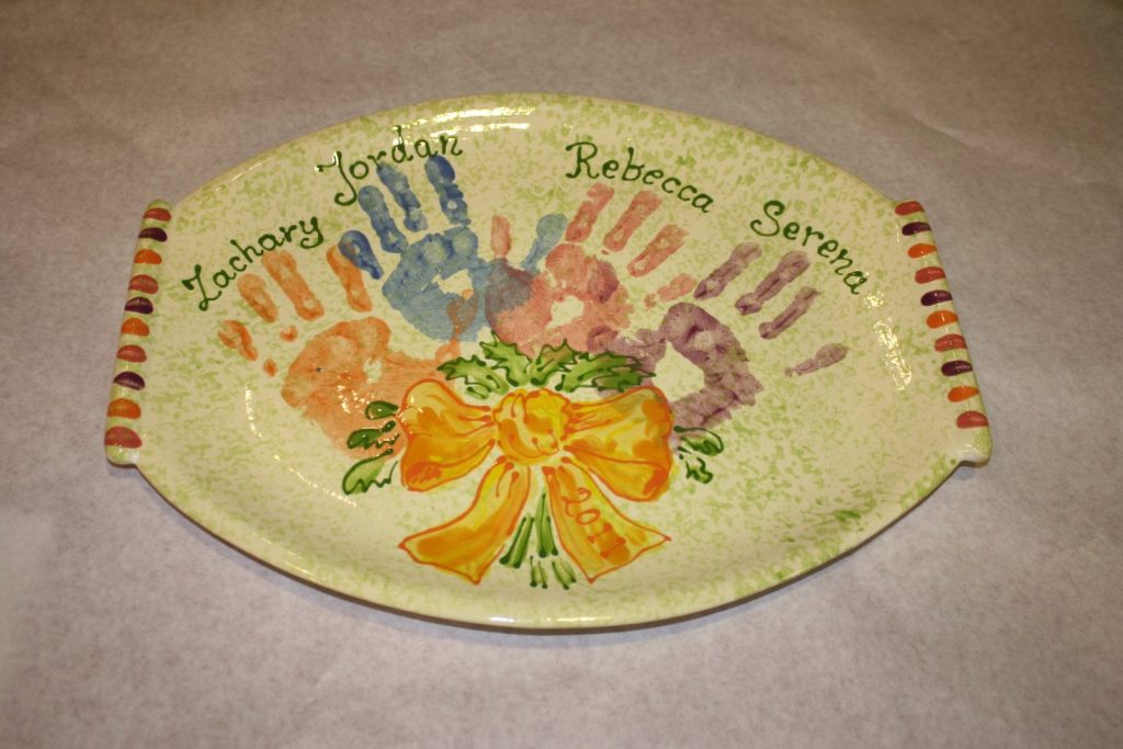 Hand-painted oval platter with overlapping colorful family handprints tied with an orange bow