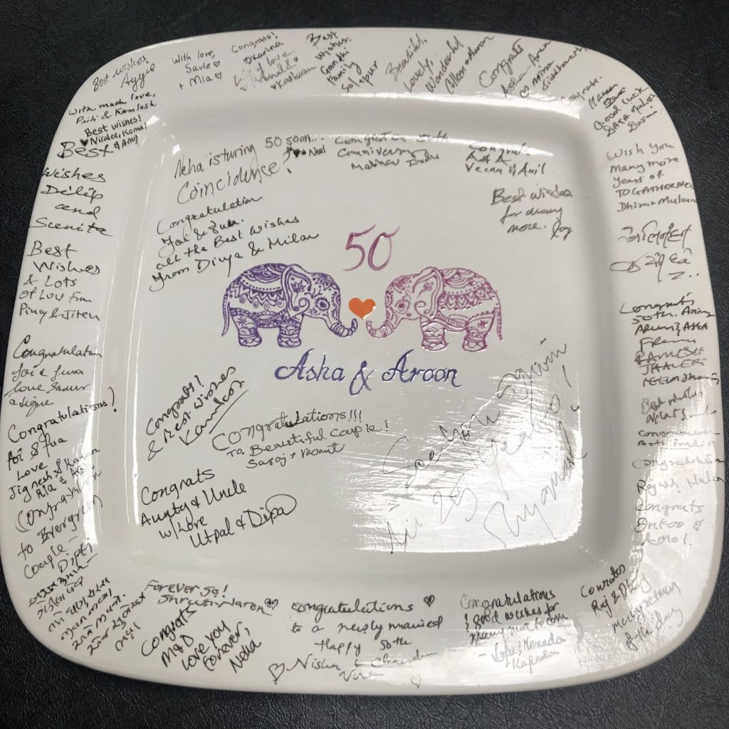 Square 50th anniversary signature platter with purple elephants, covered in guests' handwritten wishes