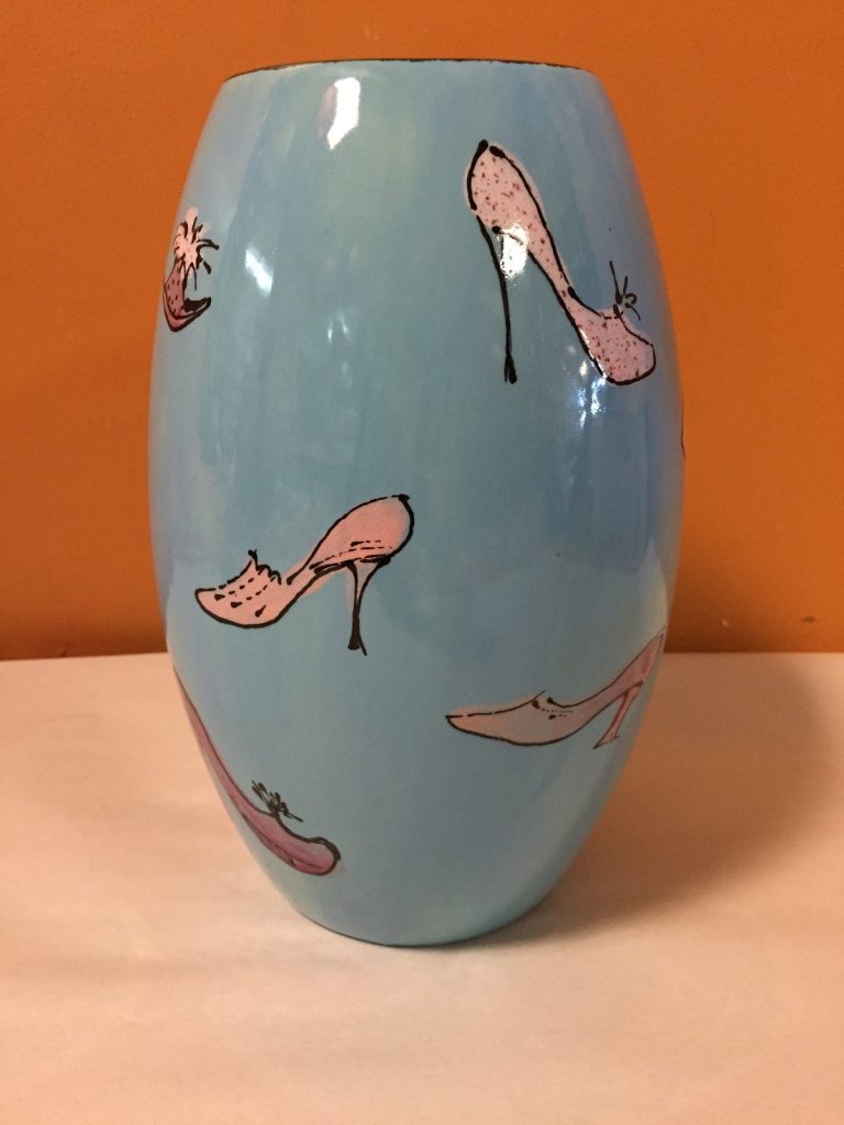 Hand-painted light blue vase with pink high heel shoes scattered around it