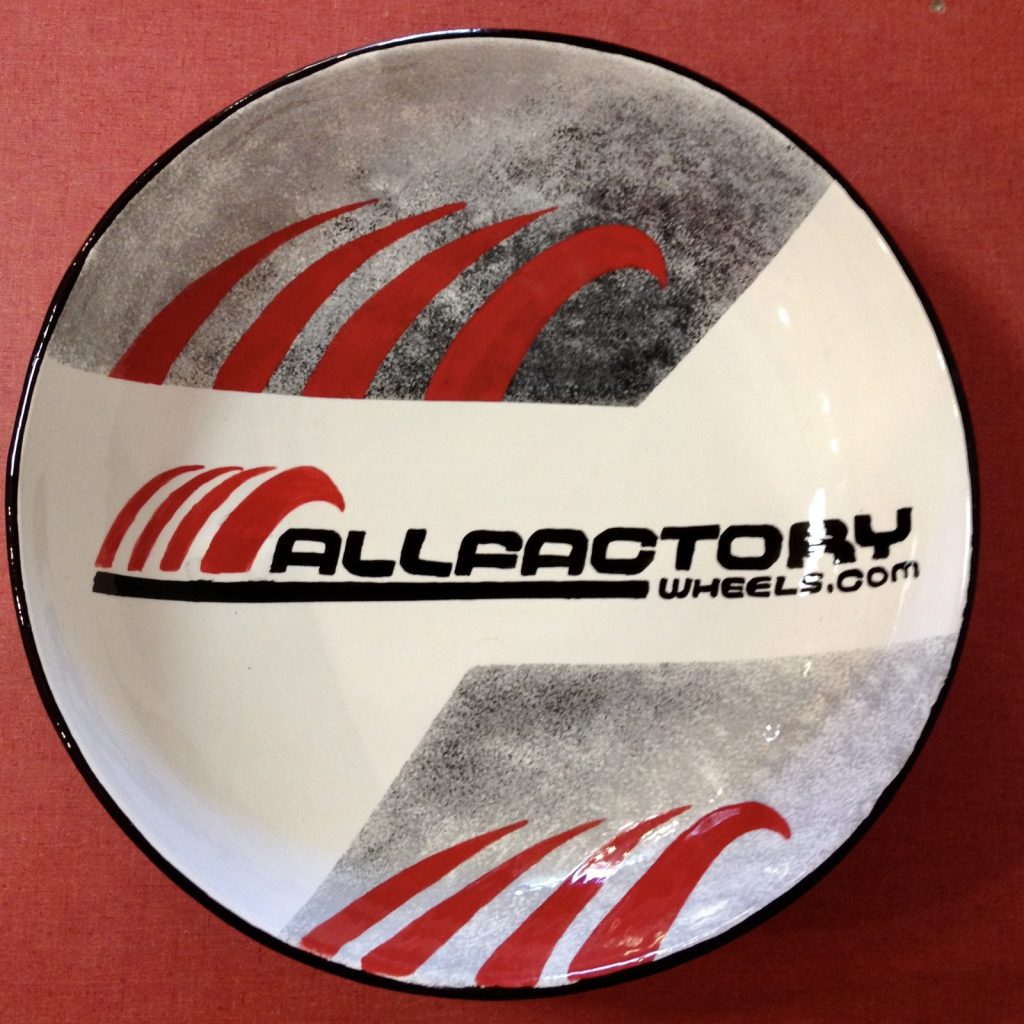 Hand-painted round bowl with a red and black wheels company logo and gray brushstrokes