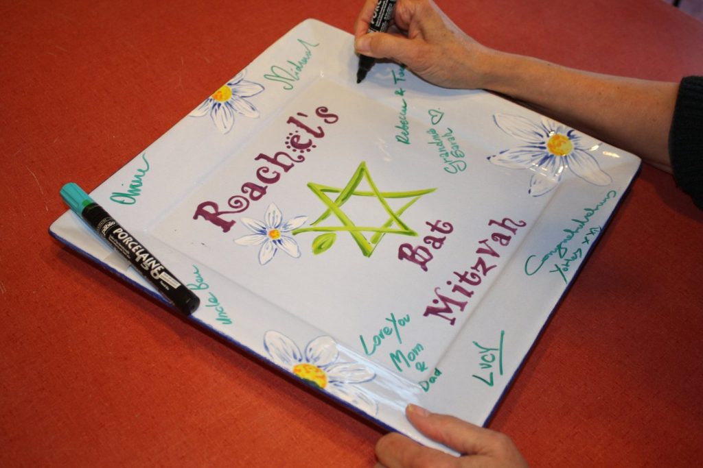Guests signing a hand-painted Bat Mitzvah platter with a green Star of David