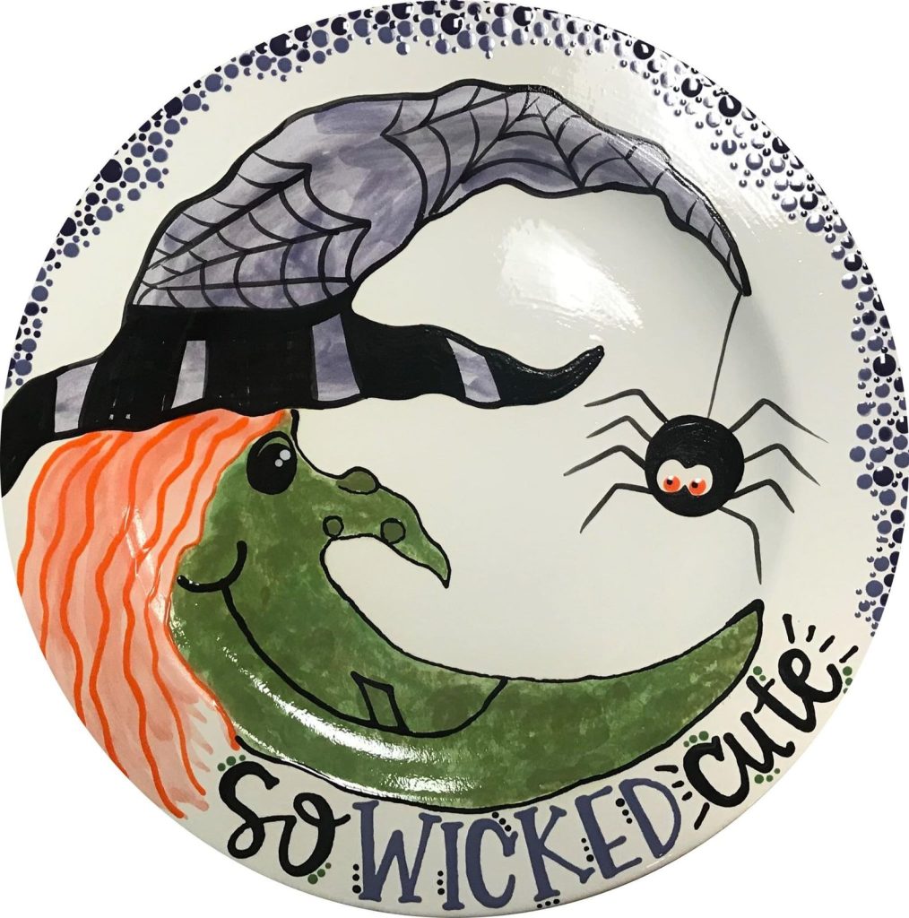 Hand-painted round plate with a smiling green witch, spider and the words So Wicked Cute