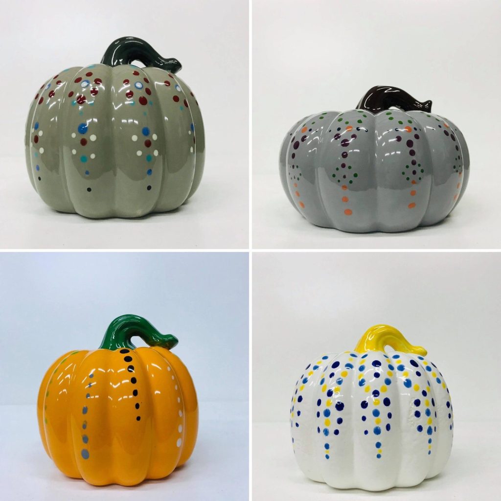Four hand-painted ceramic pumpkins in gray, orange, and white with colorful polka dots and green stems