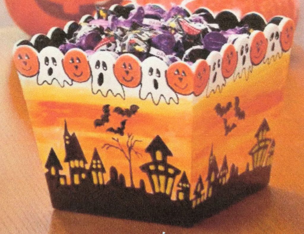 Hand-painted Halloween candy dish with ghosts and pumpkins along the rim above a haunted town silhouette