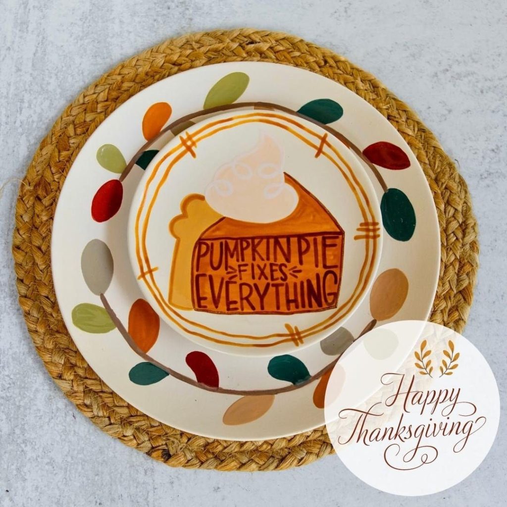 Hand-painted Pumpkin Pie Fixes Everything plate stacked on a charger with a colorful leaf border