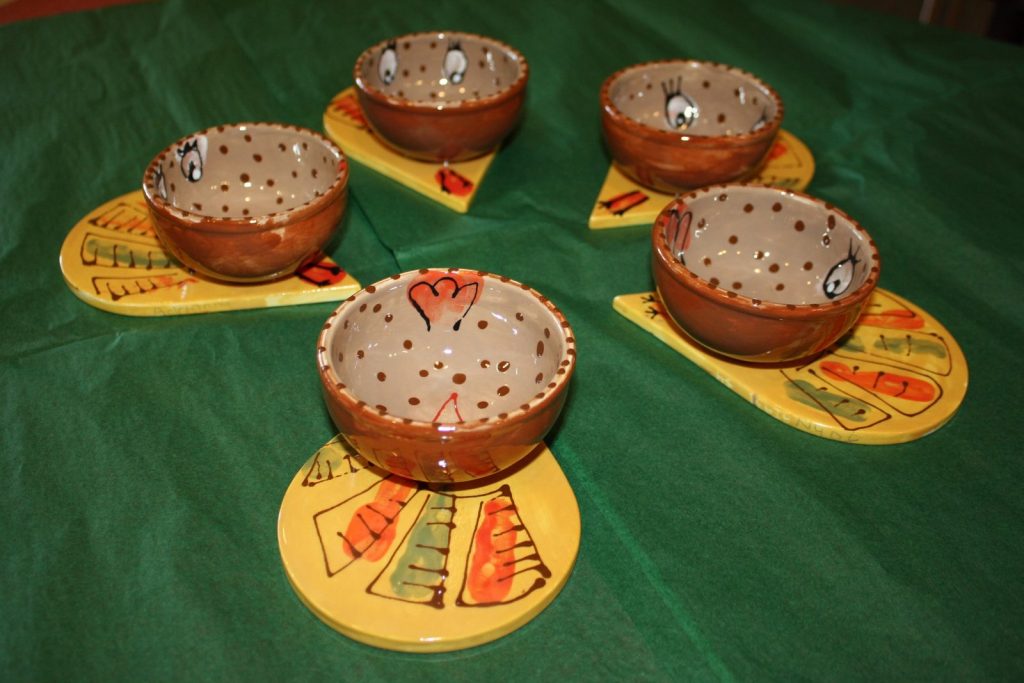 Set of hand-painted small dotted bowls on yellow triangular plates with colorful patterns