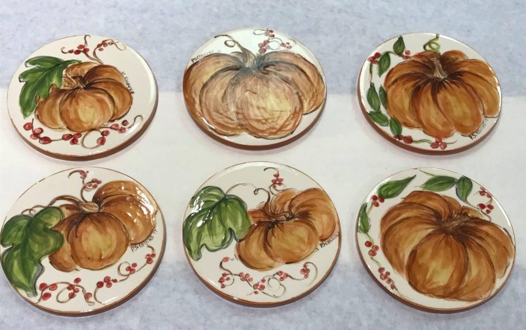 Six hand-painted round coasters with orange pumpkins and green vines