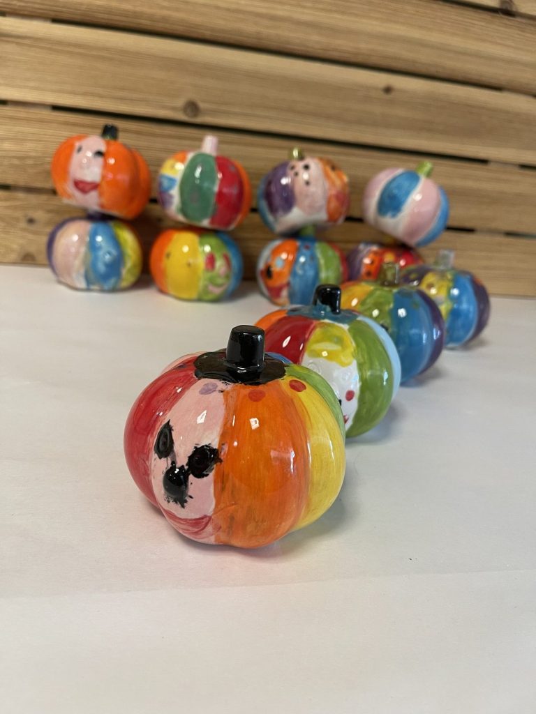 Rows of hand-painted mini pumpkins in bright rainbow colors and playful patterns
