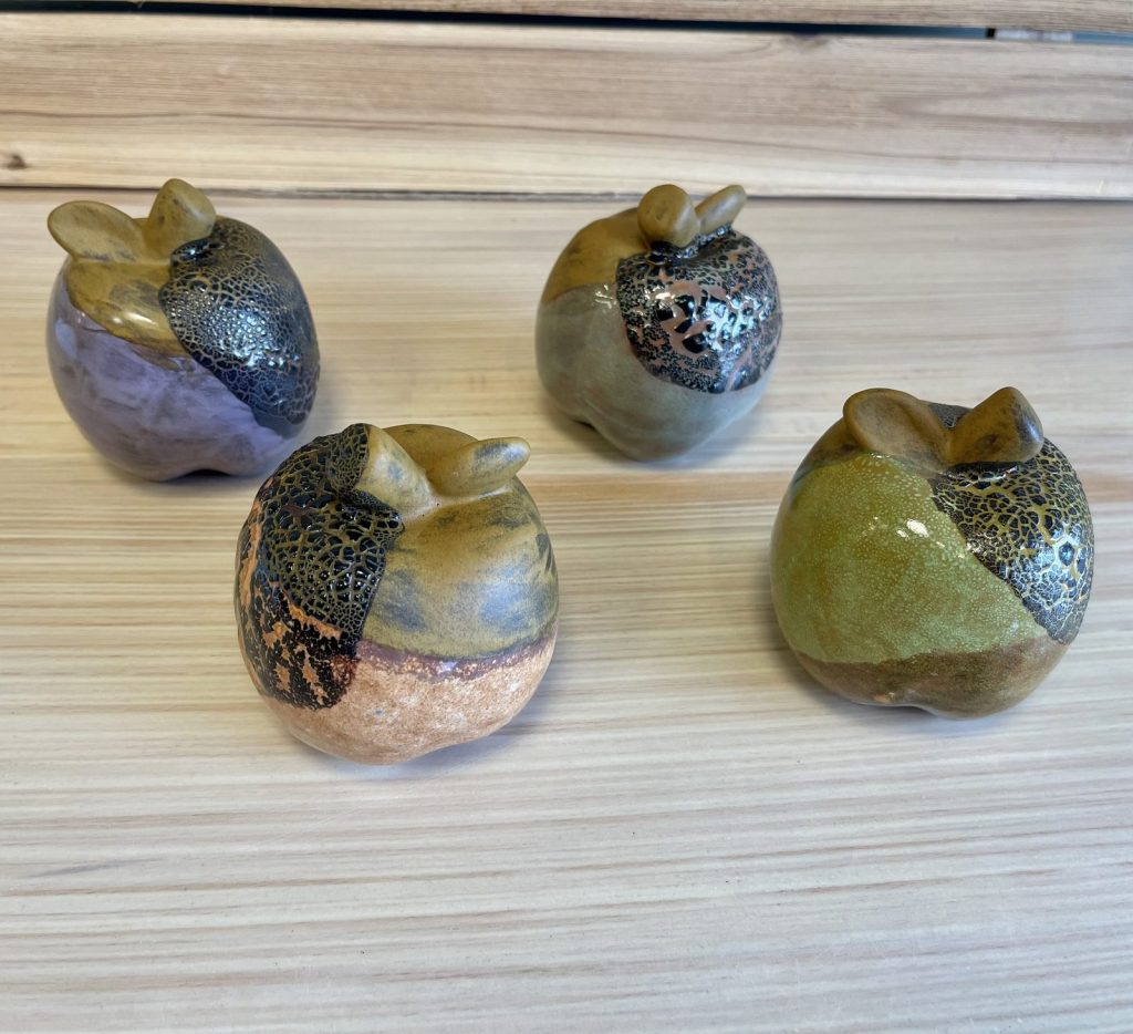 Four hand-painted apples with crackle glaze in purple, green, and gray tones