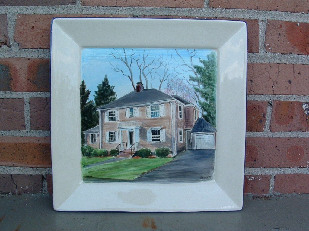 Hand-painted square platter of a tan colonial house with shutters and a garage under bare trees