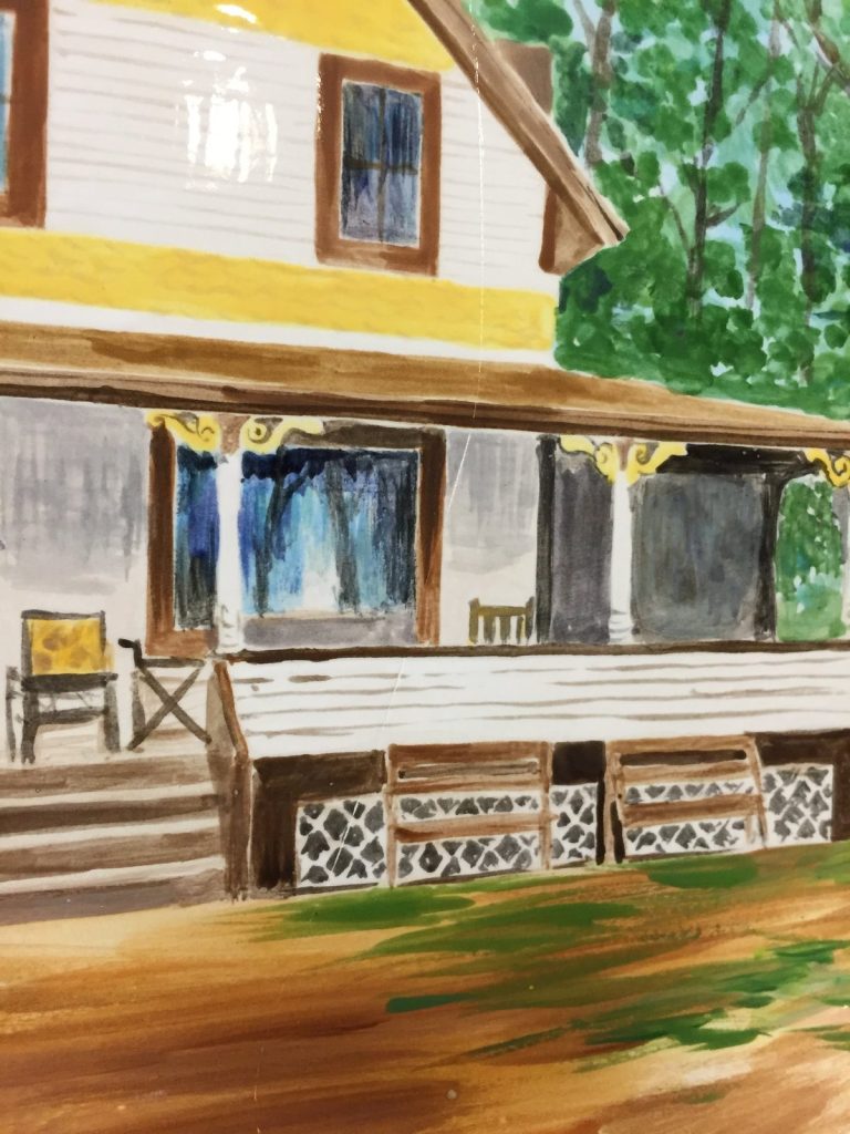 Close-up of a hand-painted yellow and white house porch with lattice and blue curtains