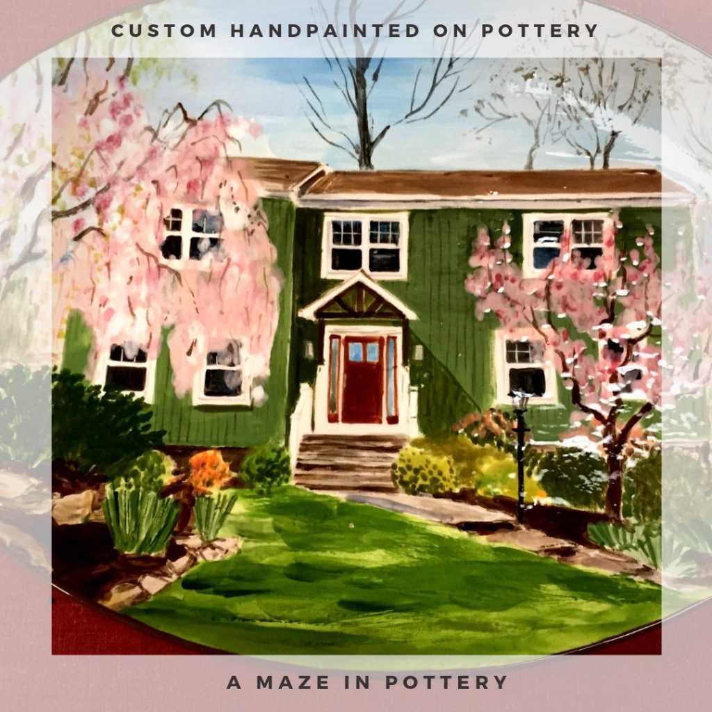 Hand-painted platter of a green house with a red door and blooming pink trees in spring