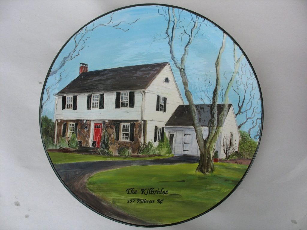 Hand-painted round platter of a white colonial house with a red door and a bare tree