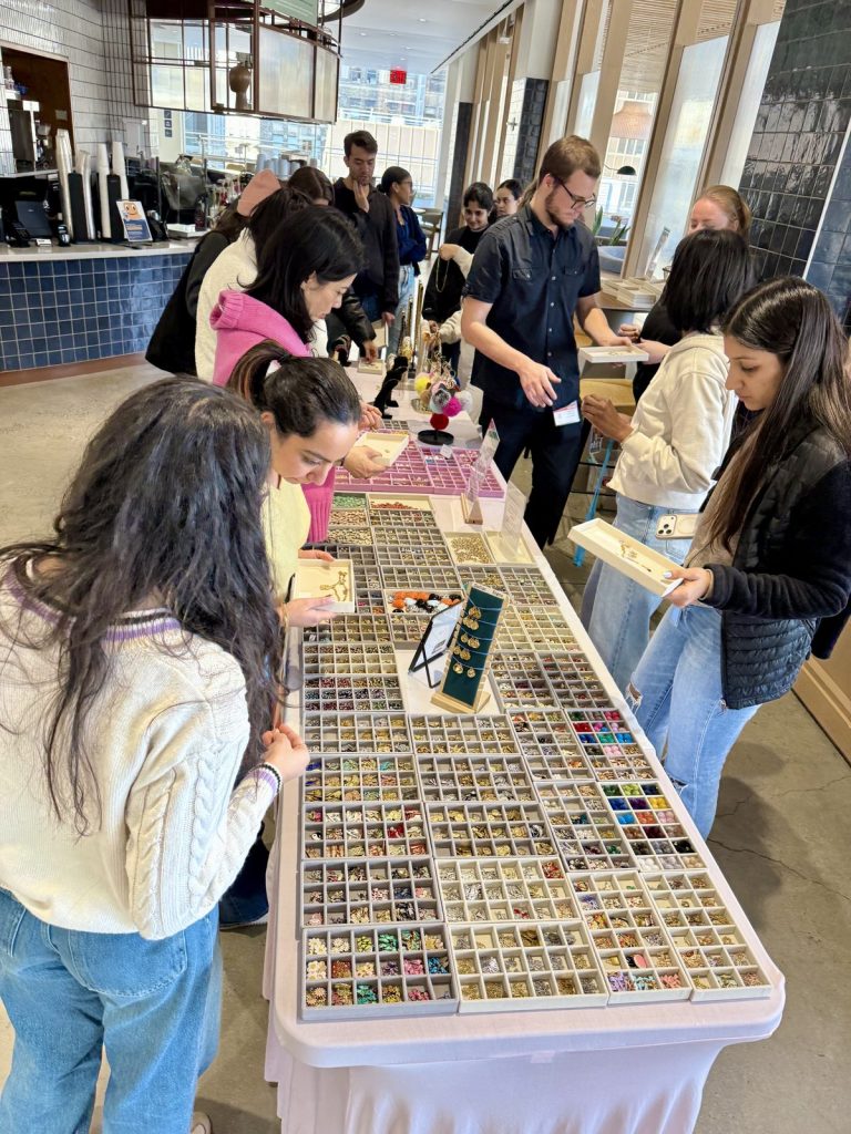 Teens choosing charms from a long table of trays at an event