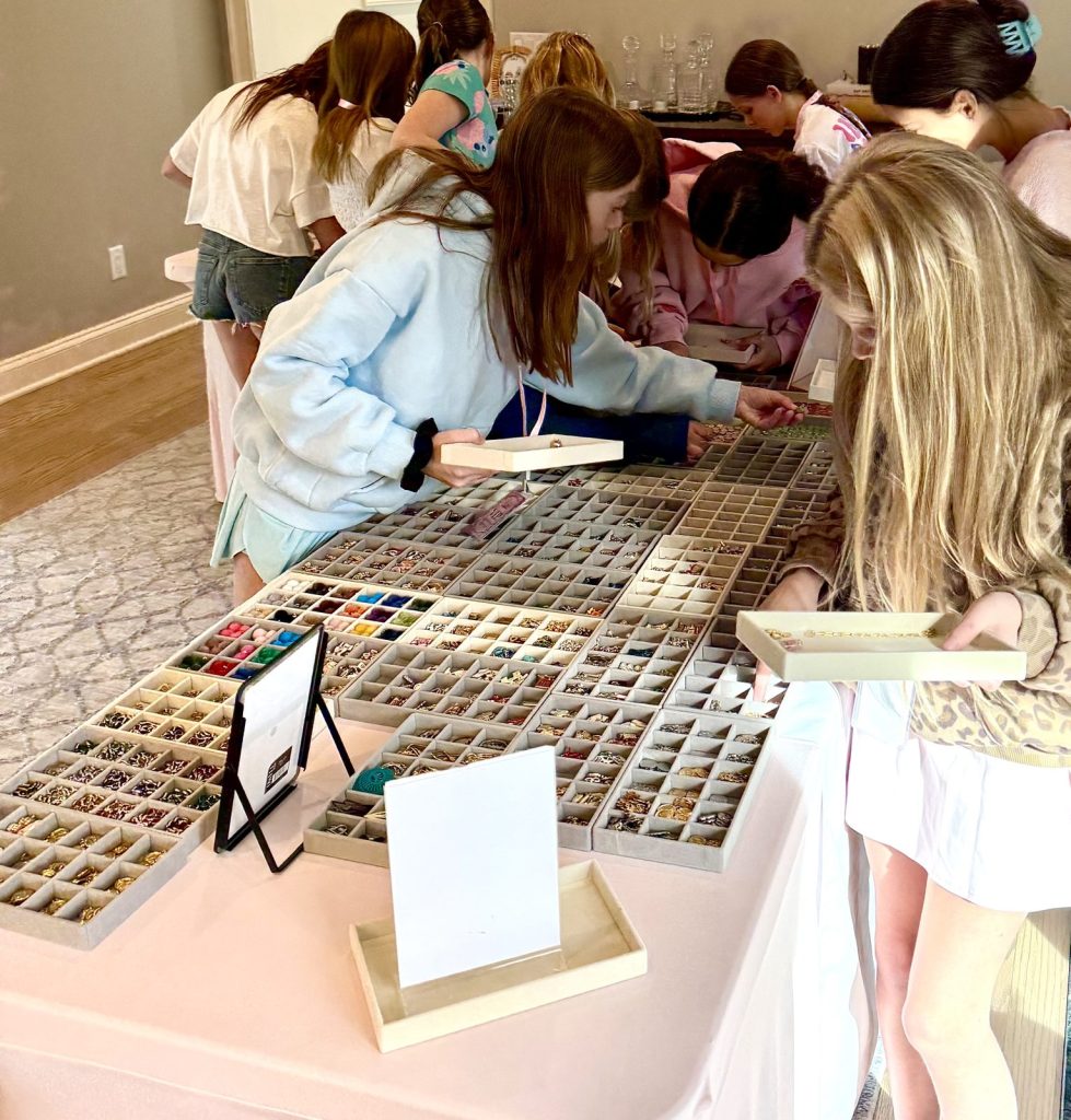 Girls leaning over the charm trays to pick their charms