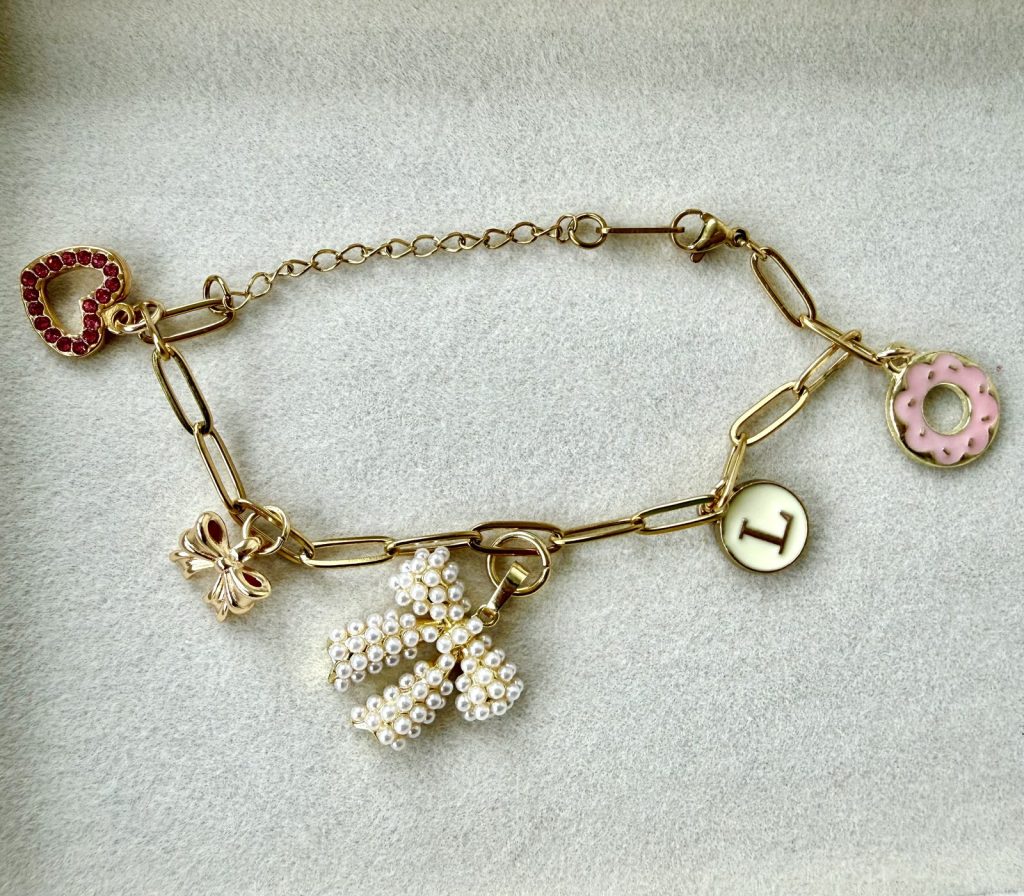 Charm bracelet with a pearl bow, a donut, a red heart and an initial L