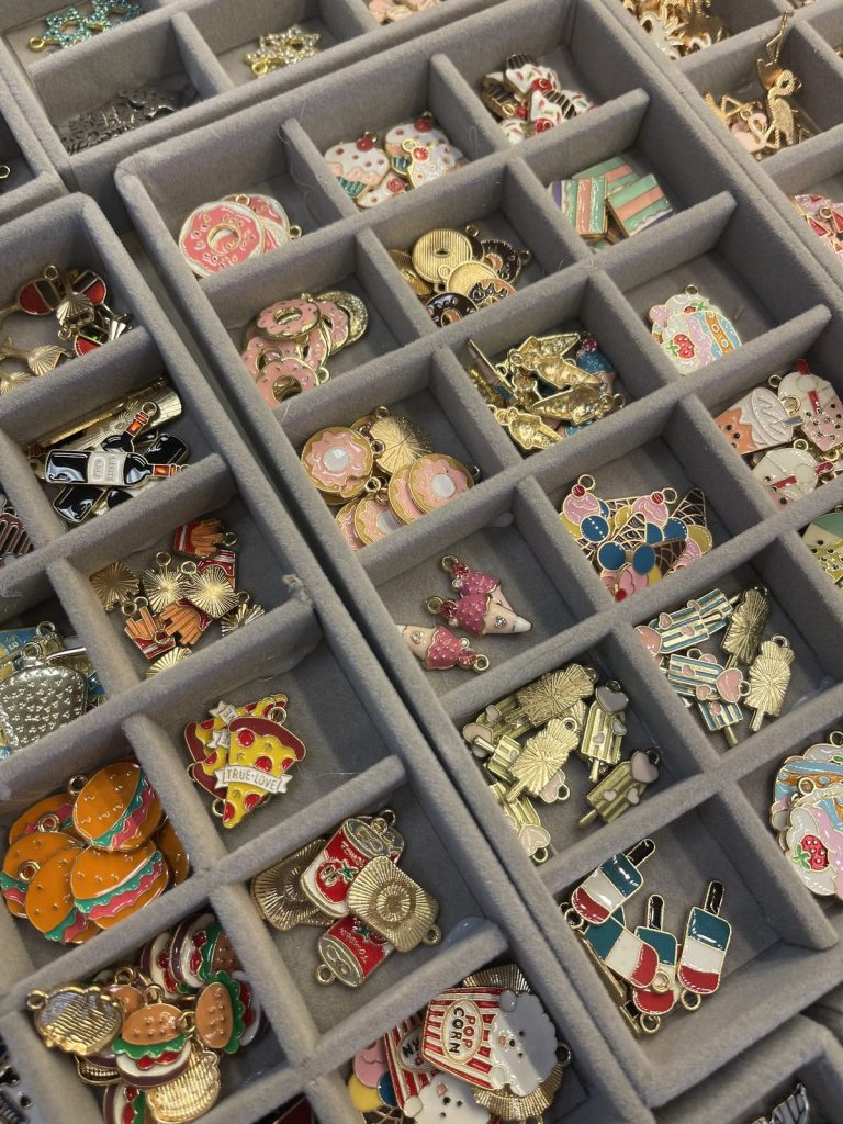 Trays of colorful enamel charms, from food to flowers