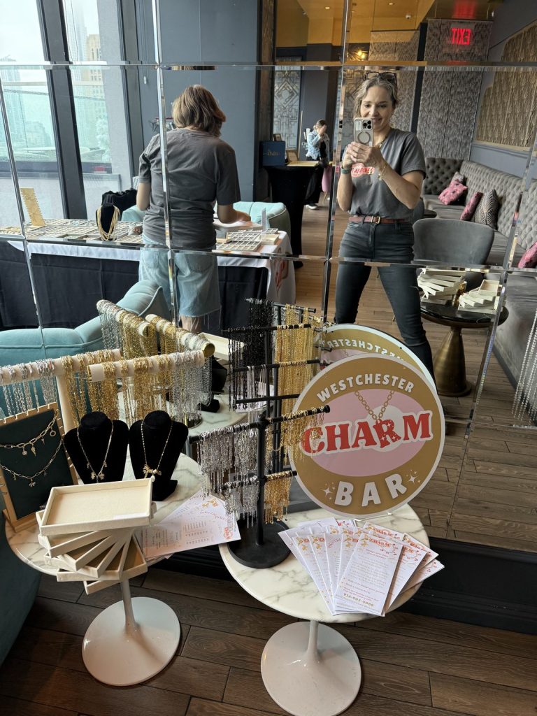Rows of charm trays on a Mobile Charm Bar table with the city skyline behind