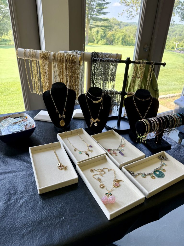 Necklace and bracelet displays with finished pieces on trays at an event