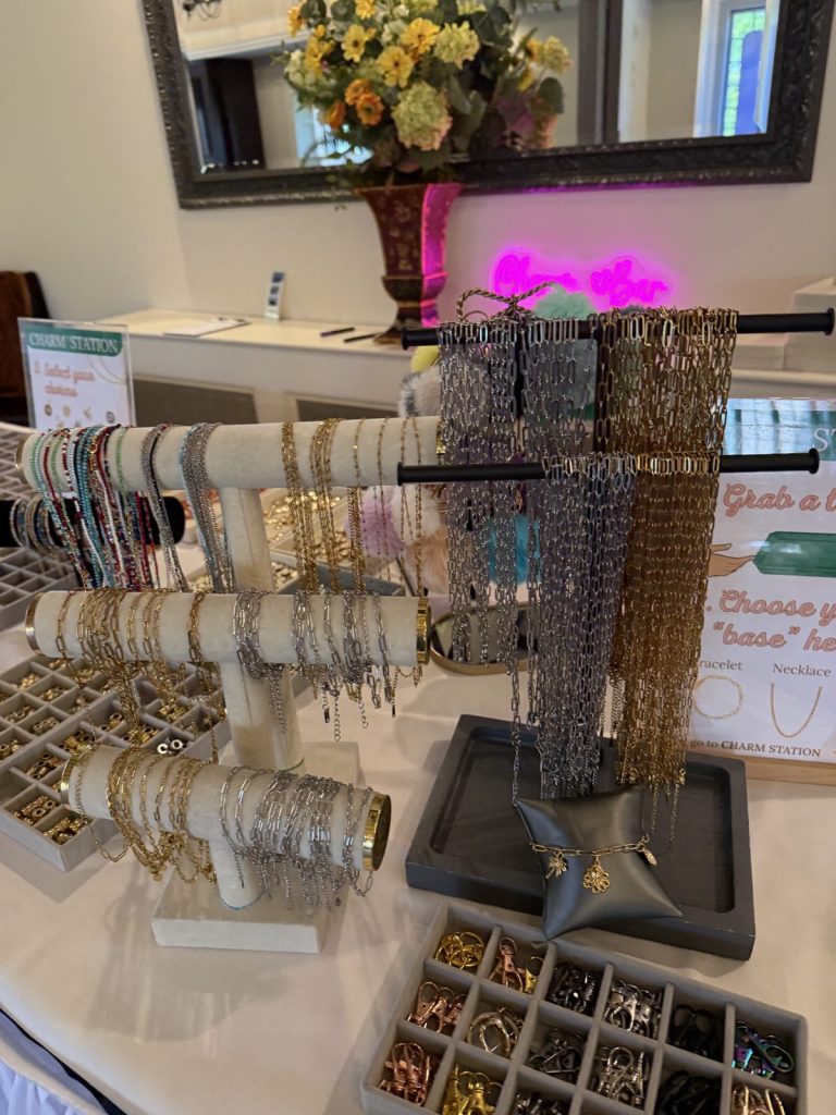 A Mobile Charm Bar setup with bracelet and necklace stands and a neon sign
