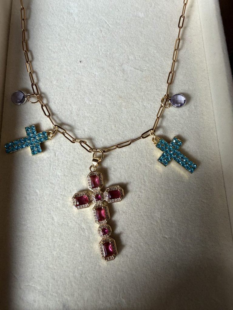 Necklace with a pink jeweled cross and two turquoise crosses