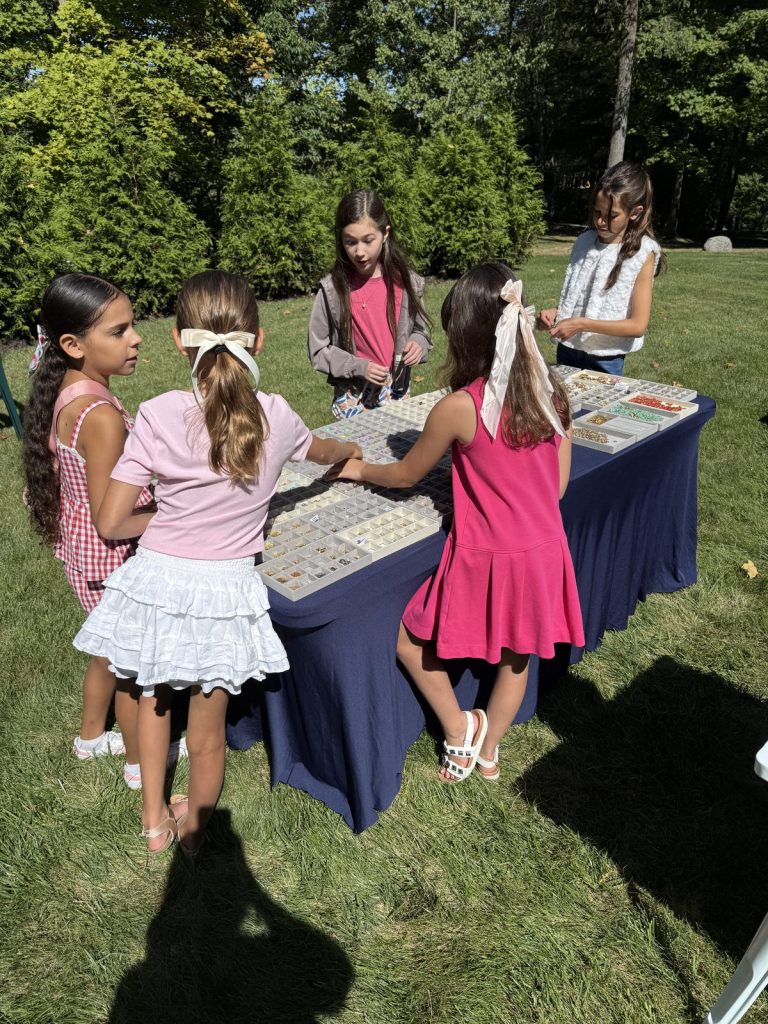 Girls choosing charms at an outdoor Mobile Charm Bar party on the lawn